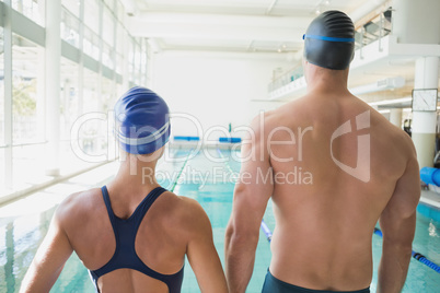Rear view of couple swimmers by pool at leisure center