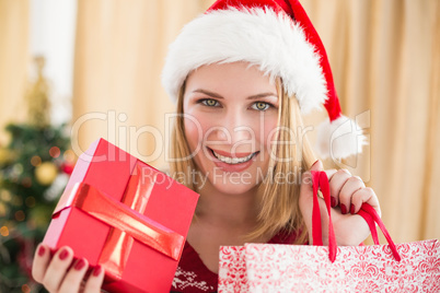 Festive blonde showing a gift while looking at camera