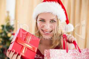 Festive blonde showing a gift while looking at camera