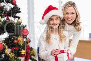 Festive mother and daughter beside christmas tree