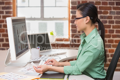 Concentrated female photo editor using computer in office