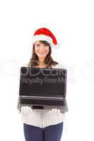 Smiling brunette in santa hat showing her laptop