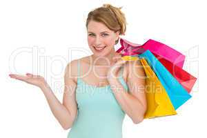 Smiling woman presenting while holding shopping bags
