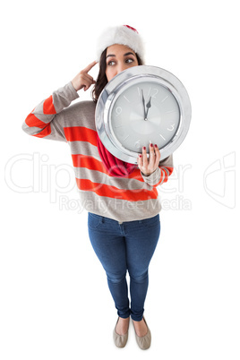 Thoughtful brunette holding a clock
