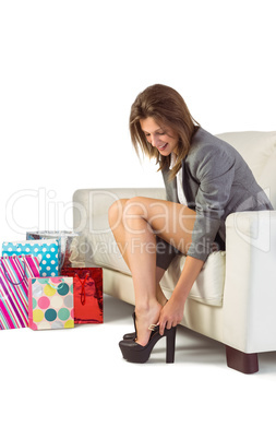 Young woman sitting on couch taking off her shoes