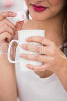 Close up of woman holding mug and marshmallow