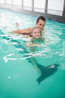 Cute little girl learning to swim with coach