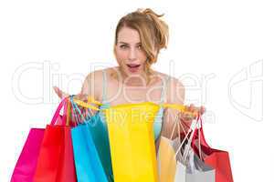 Excited woman looking at camera with many shopping bags