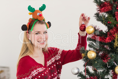 Woman hanging christmas decorations on tree