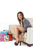 Smiling woman sitting on couch taking off her shoes