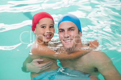 Cute little boy learning to swim with coach