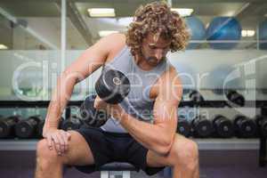 Young man exercising with dumbbell in gym