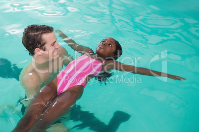 Cute little girl learning to swim with coach