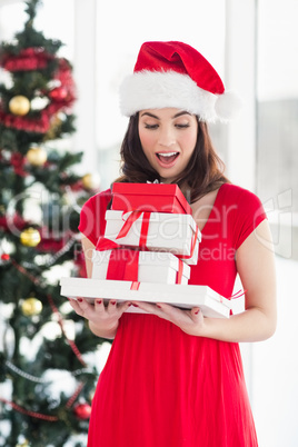 Surprised brunette in red dress holding pile of gift