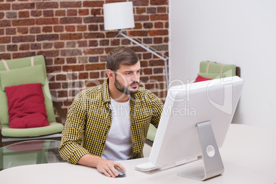 Serious casual young man using computer