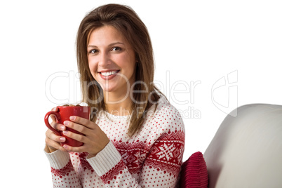 Smiling cute brunette holding cup of coffee sitting on sofa