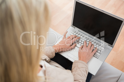 Blonde woman using laptop on couch