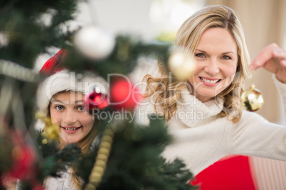 Festive mother and daughter decorating christmas tree