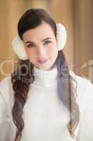 Pretty brunette with ear muffs smiling at camera