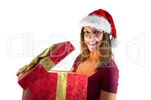Pretty brunette in santa hat opening a gift smiling at camera