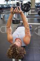 Young man exercising with dumbbell in gym