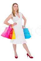 Happy blonde holding shopping bags in white dress