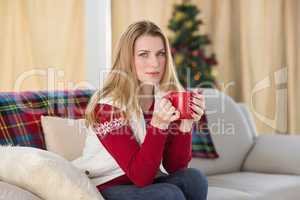 Cheerful cute blonde sitting on couch holding mug