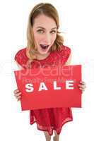Surprised blonde showing a red sale poster