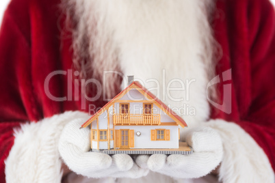 Santa holds a tiny house in his hands