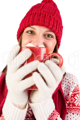 Girl in winter clothes smiling at camera behind her coffee