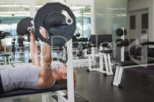 Young muscular man lifting barbell in gym