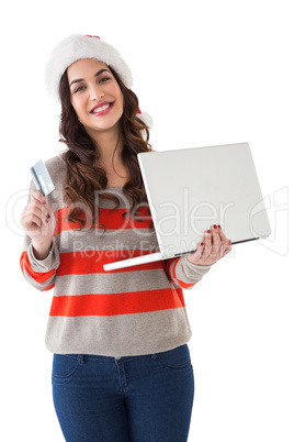 Festive brunette holding laptop and credit card