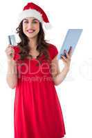 Festive brunette holding credit card and tablet