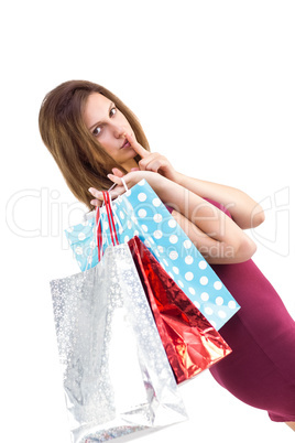 Pretty brunette keeping a secret holding gift bags