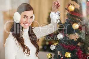 Smiling brunette holding heart near a christmas tree