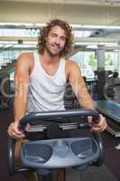 Handsome man working out on exercise bike at gym