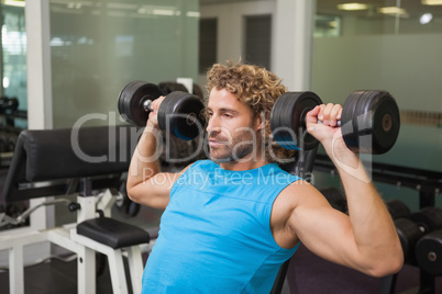 Young man exercising with dumbbells in gym