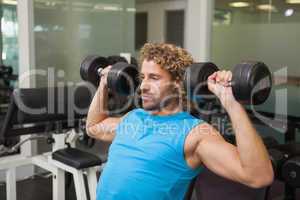 Young man exercising with dumbbells in gym