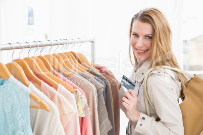 Pretty blonde smiling at camera while holding credit card