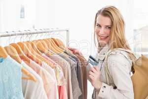 Pretty blonde smiling at camera while holding credit card