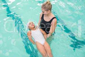 Cute little girl learning to swim with coach