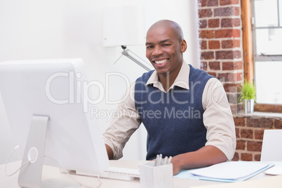 Smiling young businessman with computer at desk