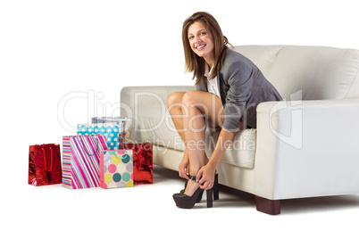 Well dressed woman sitting on couch taking off her shoes