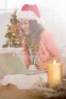 Festive brunette shopping online with laptop at christmas