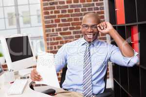 Smiling businessman with document in office