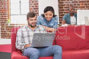 Casual colleagues using laptop on couch