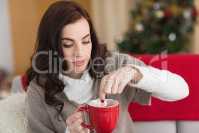 Brunette dunking marshmallow in hot chocolate at christmas