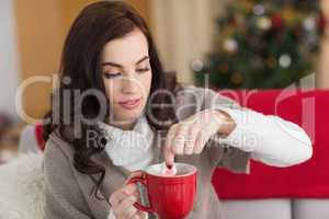 Brunette dunking marshmallow in hot chocolate at christmas