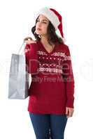 Thoughful brunette in santa hat holding shopping bag