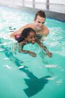 Cute little girl learning to swim with coach